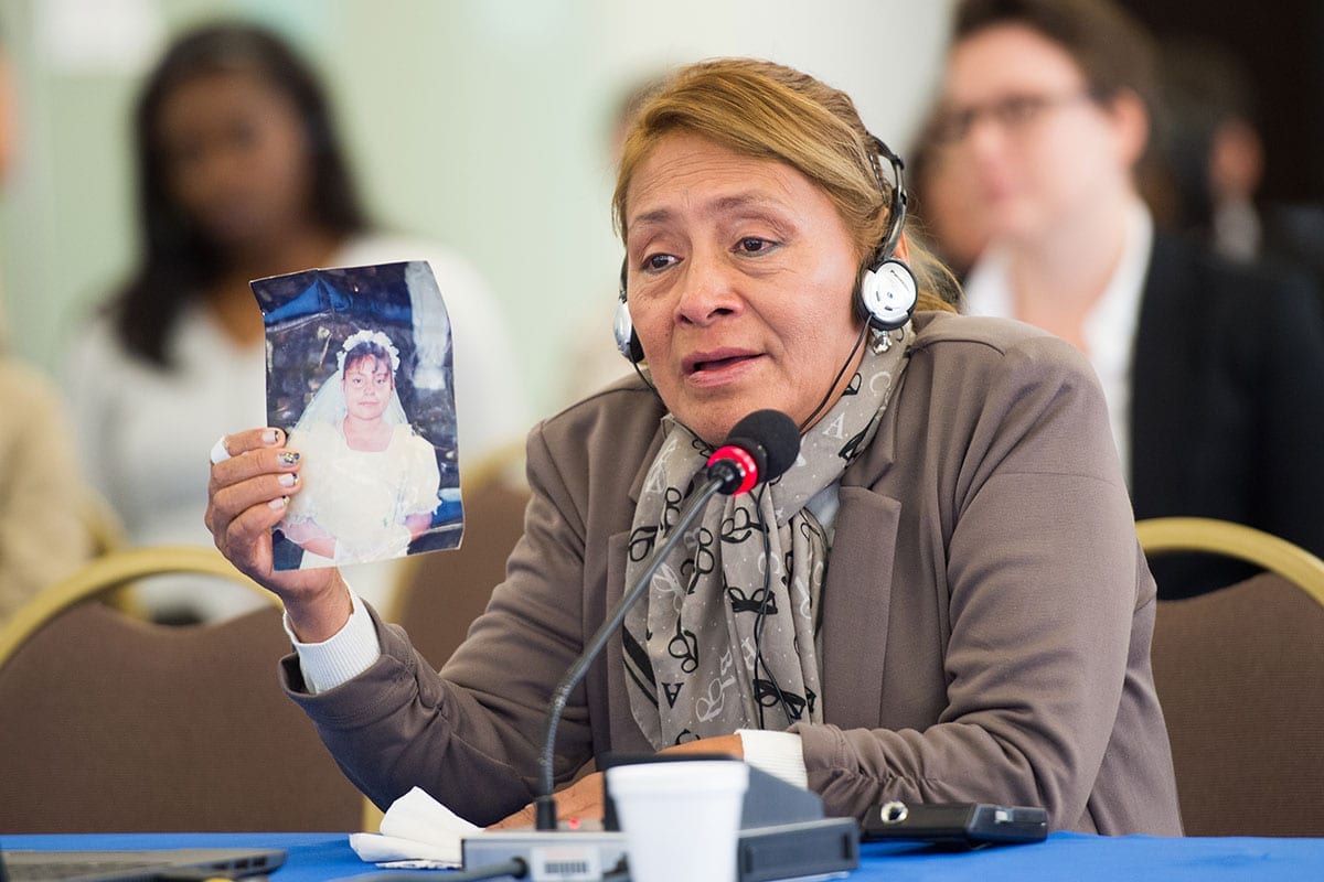 Woman holds up photo of Paola, her daughter, in court Protecting Schoolgirls from Sexual Violence in Latin America