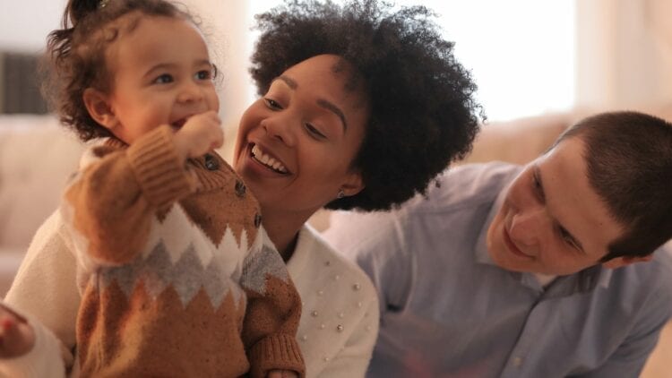 two parents smiling with a toddler