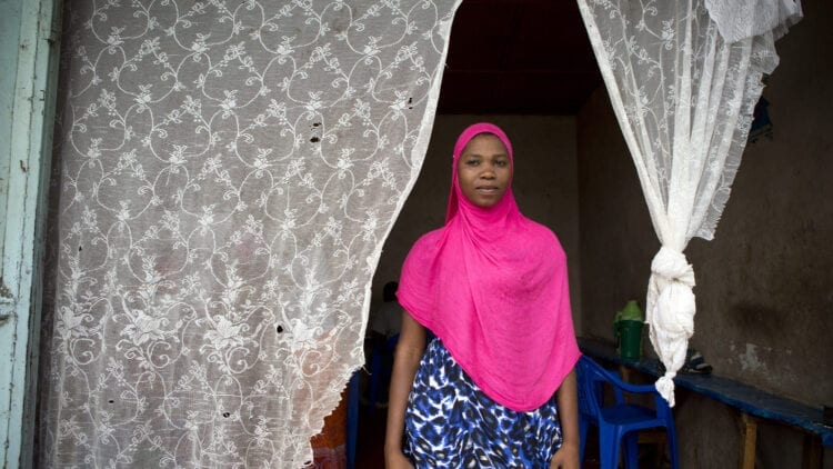 Young African woman standing in entryway with white curtain behind her