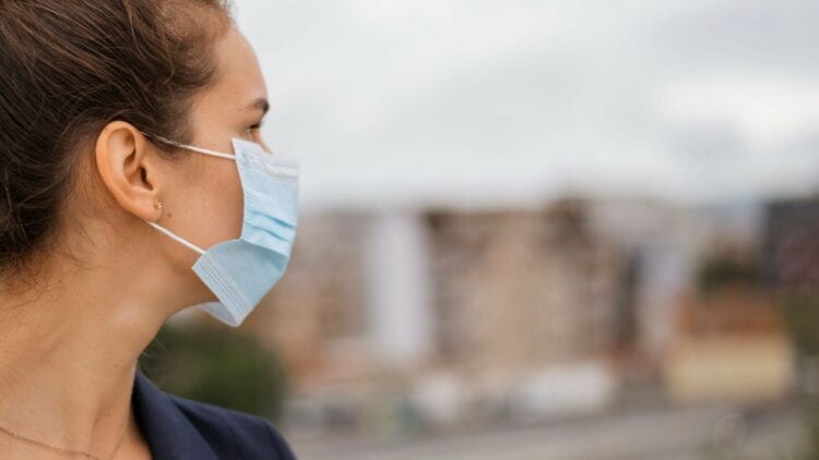 woman wearing a medical face mask looking out in the distance