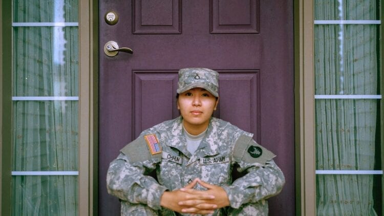 Female servicemember sitting on a step with hands folded