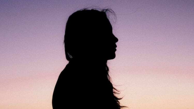 Silhouette of woman with long hair with sunset in background