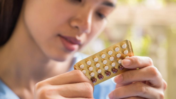 Young woman examines her birth control pills