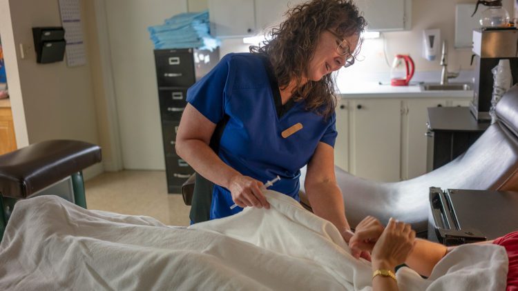 clinician nurse tending to a patient in a hospital bed, clinic, clinician