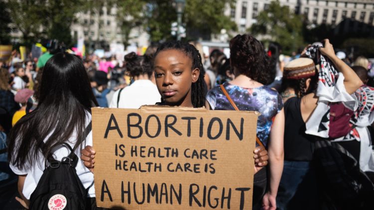 woman holding sign, abortion is a human right