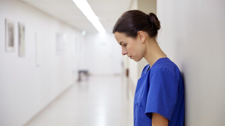 sad female clinician or nurse at hospital corridor