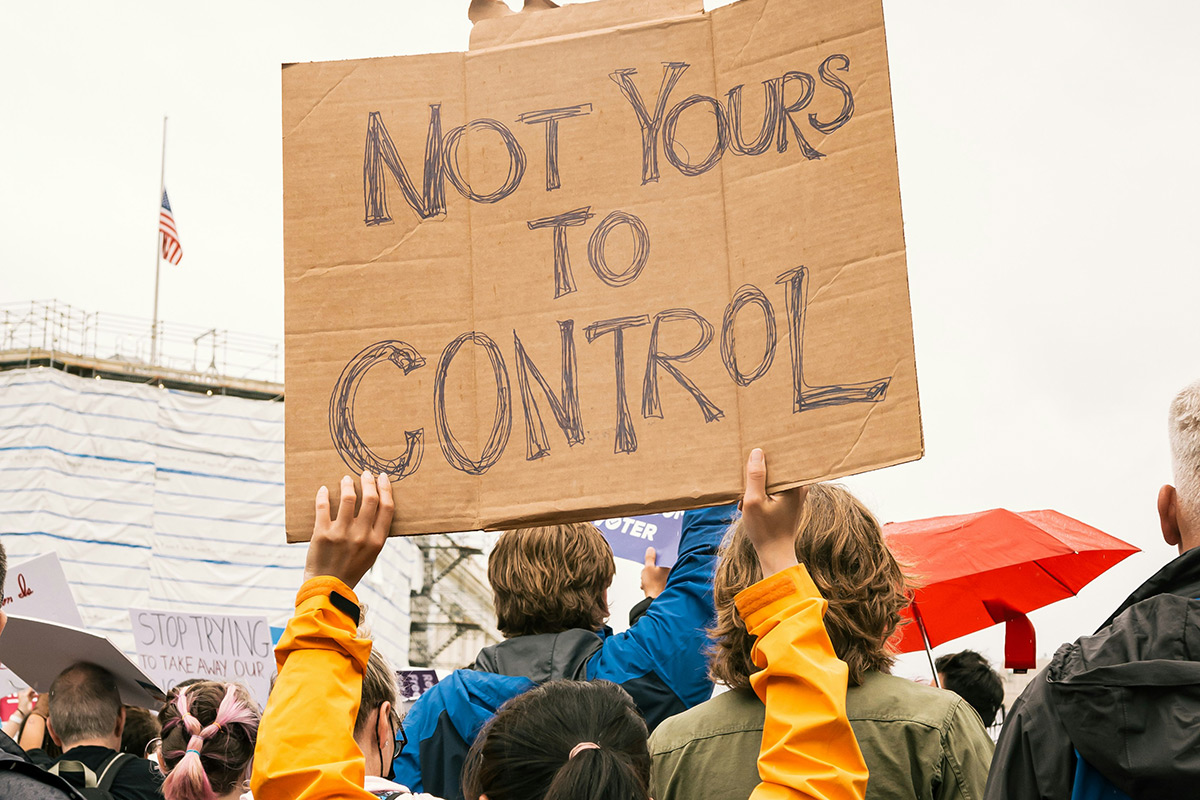 Not Yours to Control written on a protest sign