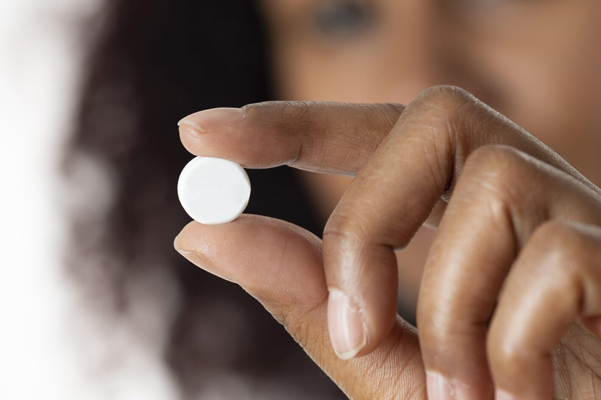 Woman holding a white pill