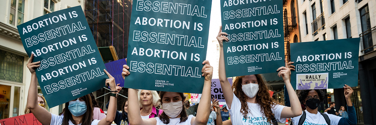 people carrying signs in the street that say Abortion is Essential