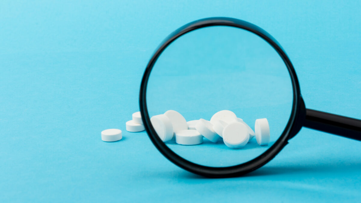 white pills viewed through magnifying glass