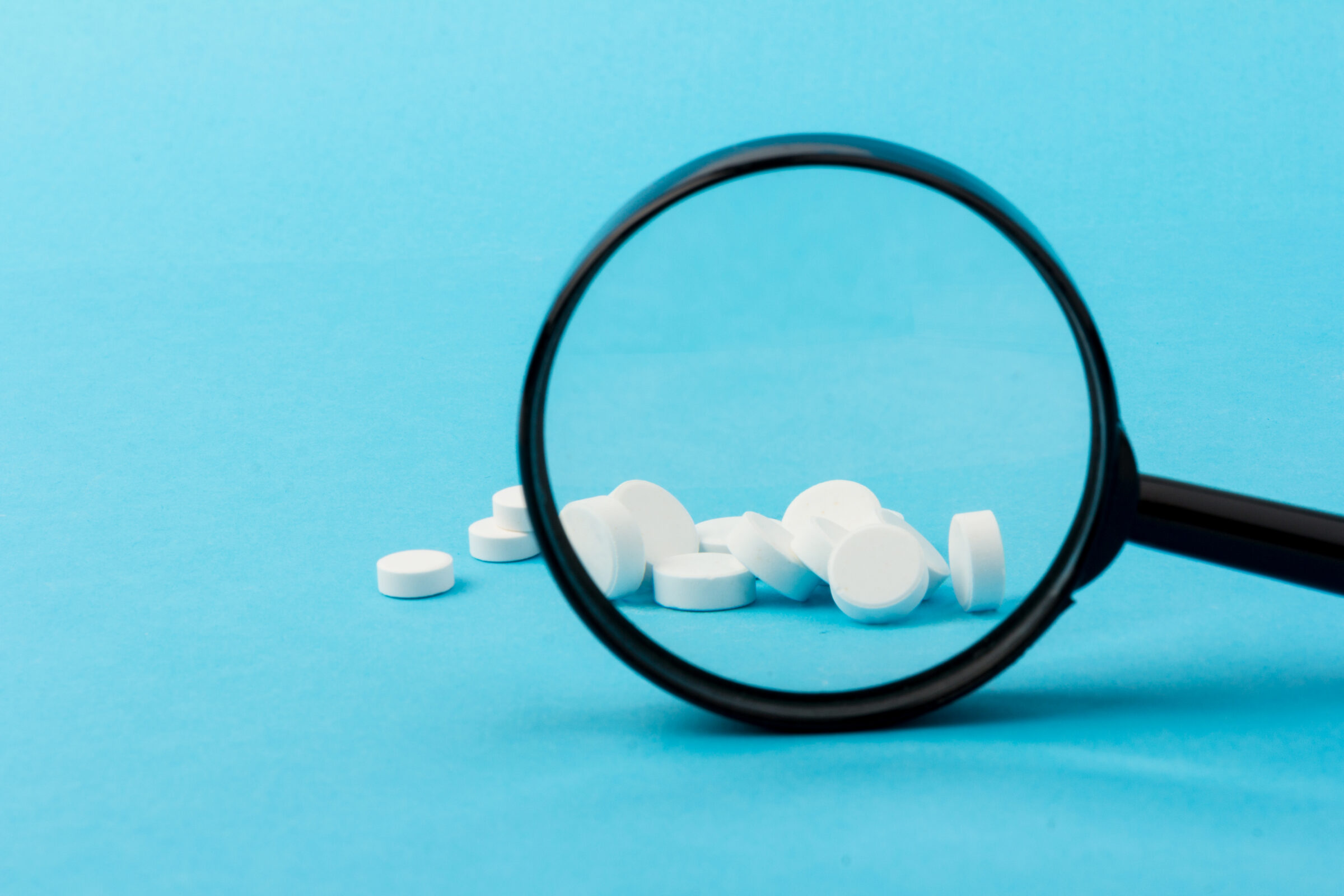 white pills viewed through magnifying glass
