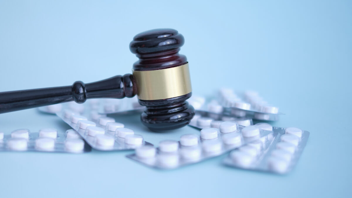 Gavel and pills on a blue background.