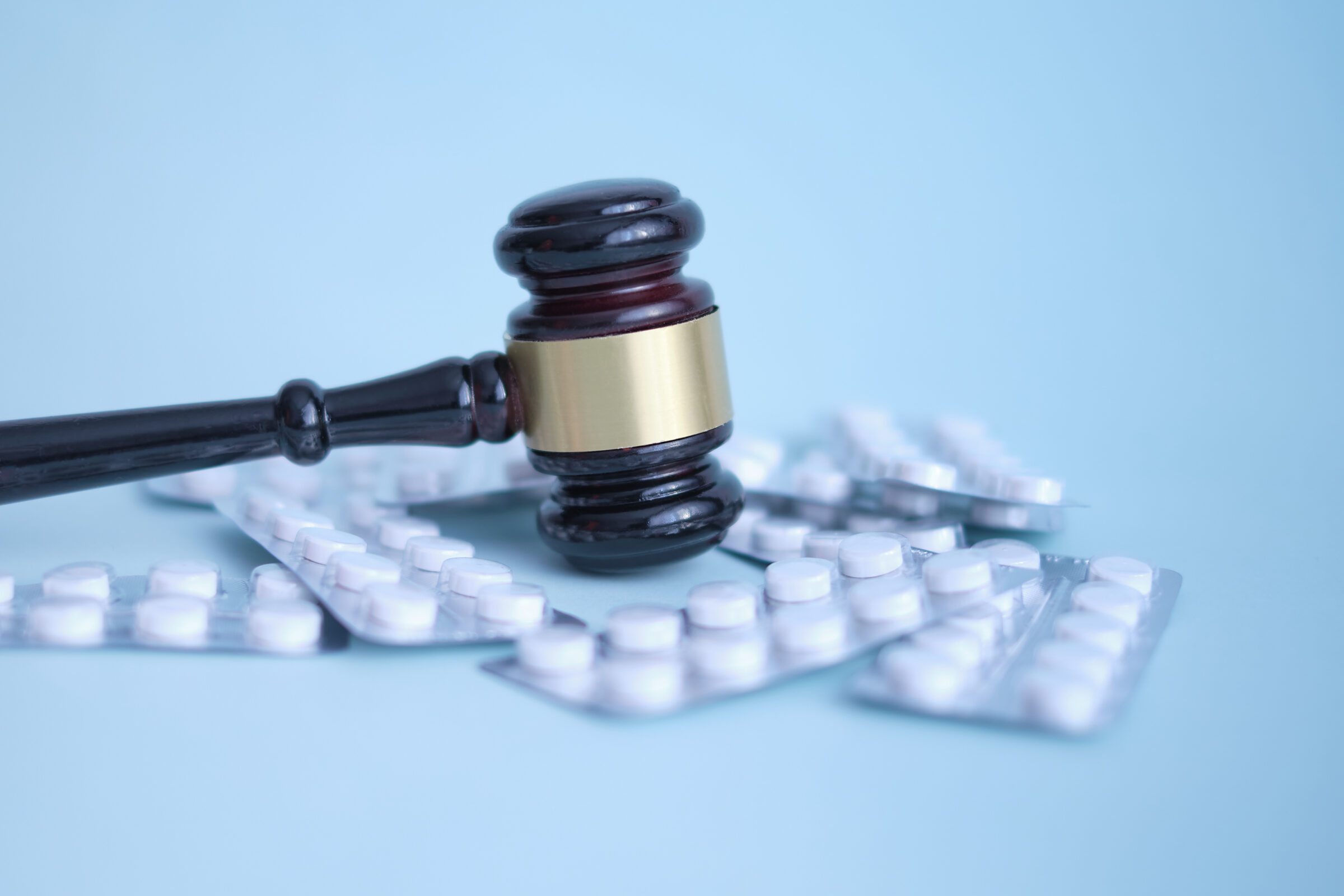 Gavel and pills on a blue background.